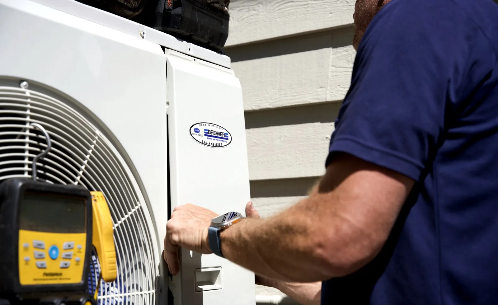 Brewer HVAC technician checking a Carrier outdoor air conditioner during maintenance