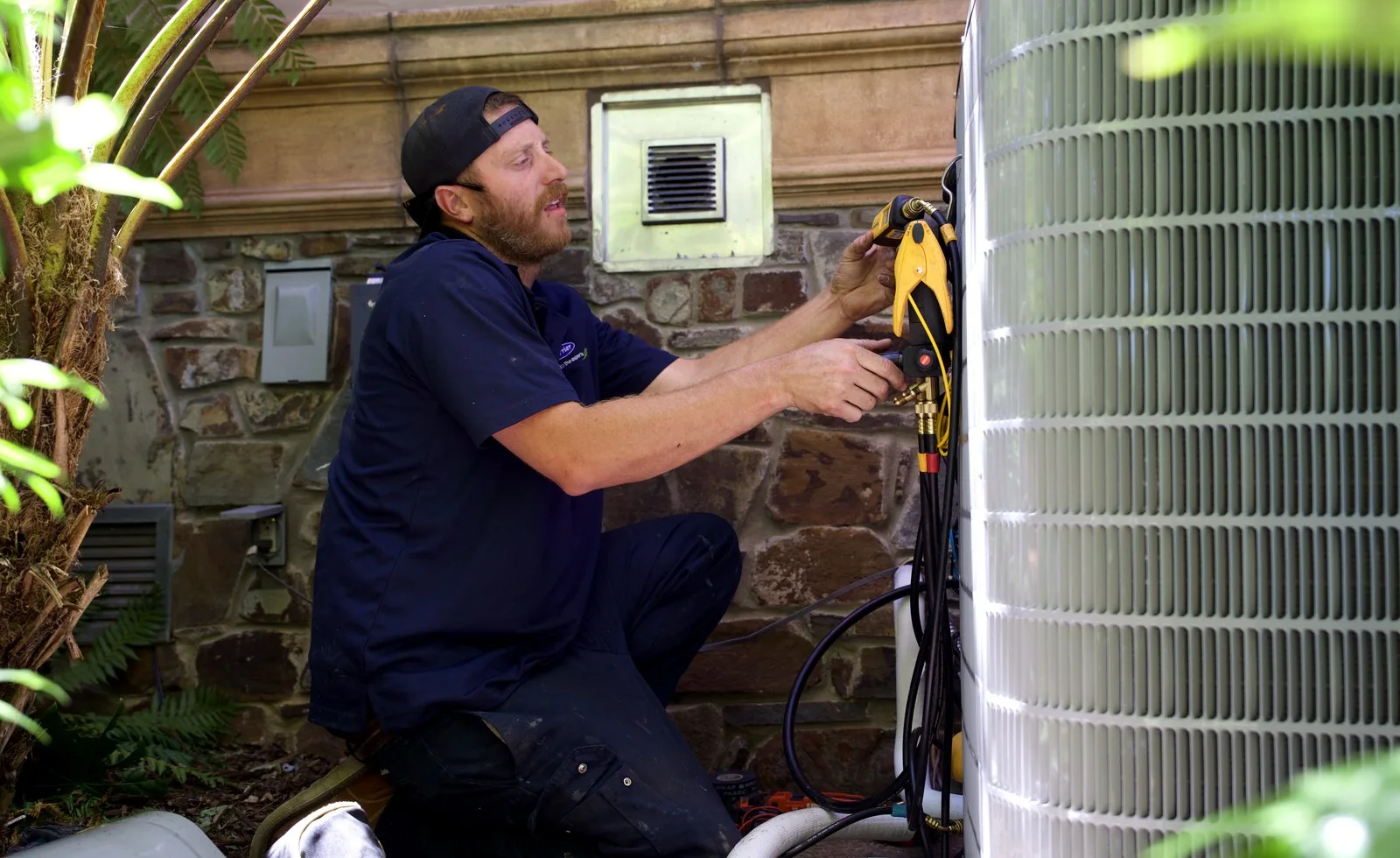 Brewer HVAC technician diagnosing an outdoor air conditioner condenser