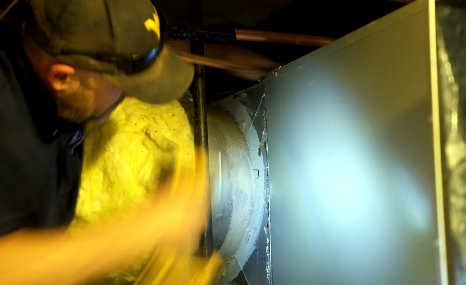 Brewer HVAC technician inspecting indoor duct and air handler equipment